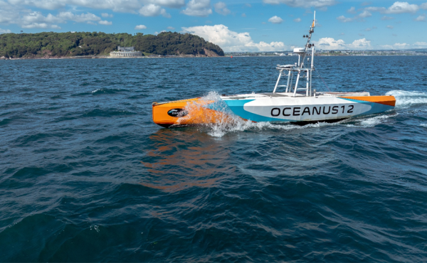 Oceanus12 autonomous uncrewed surface vessel (USV) operating at speed on open water during maritime autonomous systems testing.